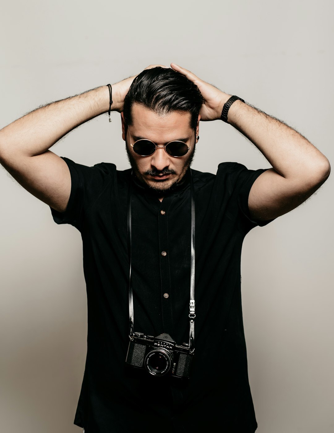 Studio portrait of a man with a camera around his neck